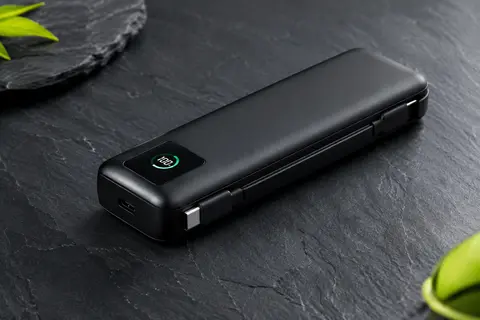 Batterie externe noire de 20 000 mAh avec câble USB-C intégré et affichage numérique, posée sur un fond ardoise
