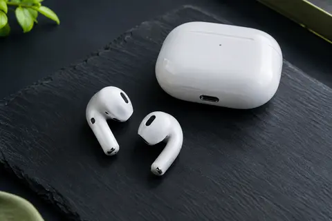 Écouteurs Apple AirPods 4 à tige courte posés à côté de leur boîtier de charge USB-C