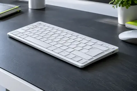 Clavier Bluetooth blanc fin à touches AZERTY, présenté sur un bureau contemporain aux tons ardoise.