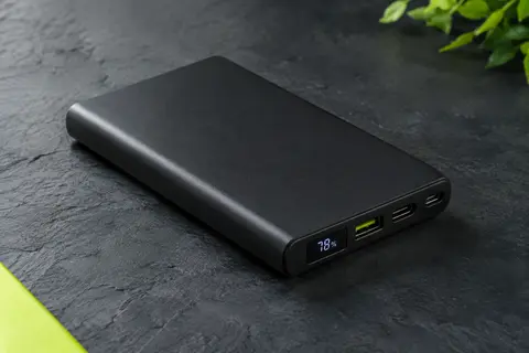 Batterie externe iPosible noire mate avec écran LCD et connecteurs, photographiée sur fond ardoise.