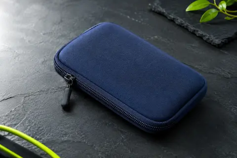 Pochette pour smartphone en néoprène bleu marine texturé avec fermeture éclair, sur fond ardoise.