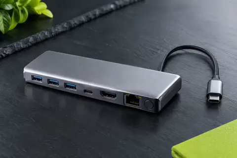 Hub USB-C argenté en aluminium avec ports USB, HDMI et Ethernet, posé sur un fond ardoise