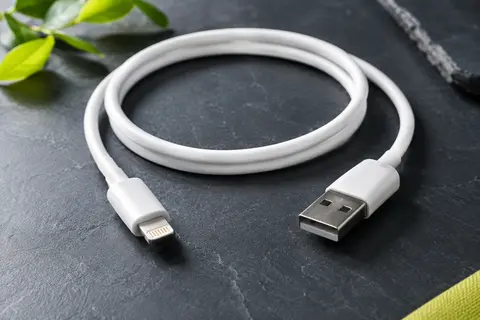 Câble RAMPOW blanc de 1 m avec connecteur Lightning et extrémité USB, posé sur un fond ardoise.