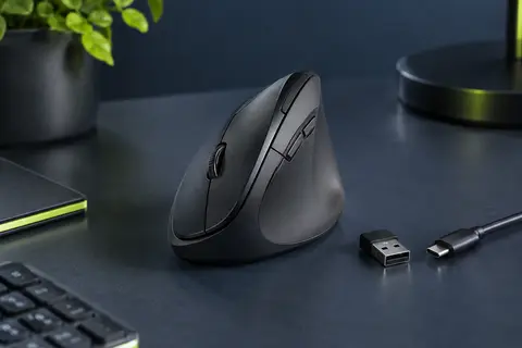 Souris verticale noire rechargeable avec récepteur USB-A, présentée sur un bureau au fond ardoise.