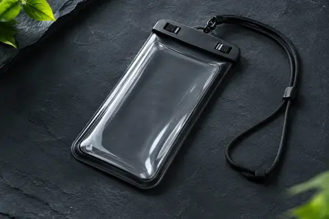 Pochette étanche YOSH noire en PVC transparent avec fermeture à clip et cordon sur fond ardoise.